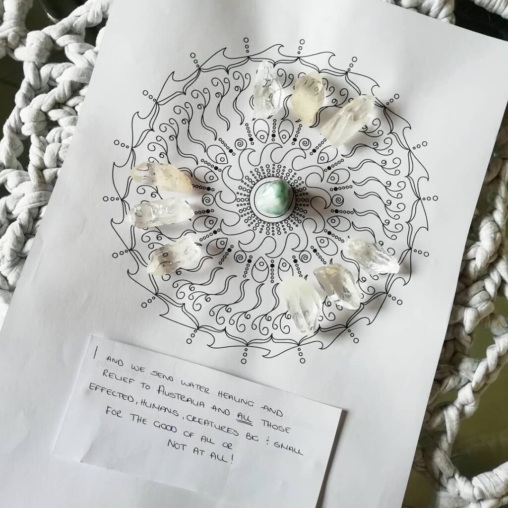 "How to use Oracle Mandalas: Crystal Grids" depicts a beautiful crystal grid upon the Ocean Flow Mandala using Clear Quartz Points and a tumbled piece of Larimar.